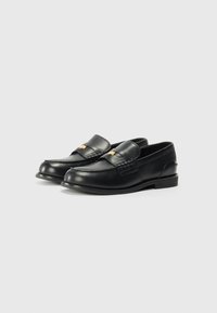 Schwarze Lederloafers mit einem niedrigen Absatz, die ein gestepptes Design und einen dekorativen Riemen auf der Vorderseite aufweisen. Glatte Textur mit dezentem Glanz.