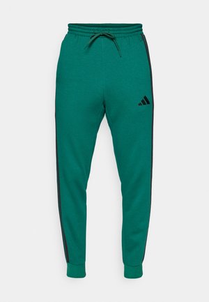 Gröna bomullsjoggers med svarta sidostrecker, elastisk midja med dragsko, tapered ben och en Adidas-logotyp på vänster lår.