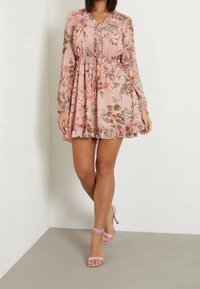 Floral pink dress with long sleeves, v-neck, cinched waist, and ruffled hem. Paired with light pink ankle strap heels.