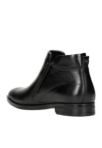 Schwarze Lederstiefelette mit seitlichem Reißverschluss, abgerundeter Spitze und strukturierten Akzenten an der Ferse. Robuste Gummisohle mit minimalem Profil.