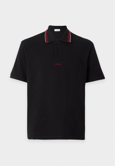 Polo noir à manches courtes avec col boutonné présentant une bordure rouge à motif et un petit logo rouge Versace sous les boutons.