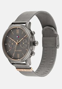 Montre Tommy Hilfiger avec un cadran gris foncé, des accents en or rose, un bracelet en maille d'acier inoxydable et des chiffres romains. Deux sous-cadrans affichés.