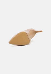 Tacco a punta color beige con tomaia in pelle liscia, tacco sottile e suola in gomma texturizzata. Marchio discreto sulla suola.