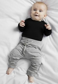 Schwarzes Langarmoberteil und graue Jogginghose mit Kordelzugbund. Die Hose hat ein Bündchen an den Knöcheln und einen weichen, strukturierten Stoff.