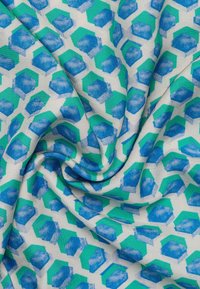Multicolored fabric featuring a geometric pattern of blue and green hexagons on a cream background, displaying a smooth, textured weave.