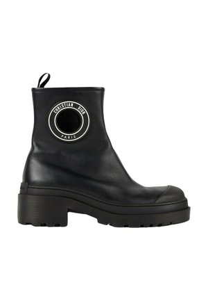 Bottine en cuir noir avec semelle épaisse et écusson rond portant le logo "Christian Dior Paris" sur le côté.
