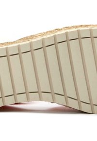 Rubber shoe sole with a textured, ridged pattern. Color is light beige with a natural jute accent at the edge. Curved shape enhances comfort.