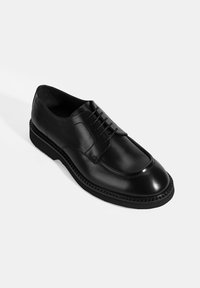 Schwarzer Lederschuh mit runder Zehenform und Schnürdesign. Mit glatter Oberfläche, subtiler Naht und einer robusten Gummisohle.