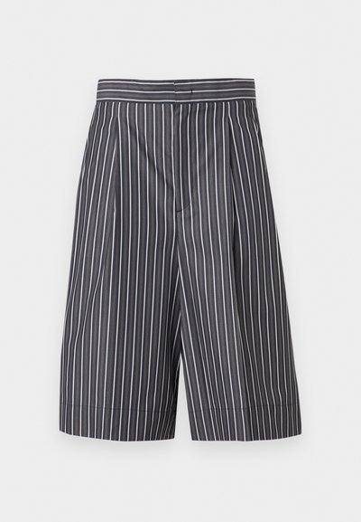 Μαύρα και λευκά κάθετα ριγέ σορτς με φαρδιά μπατζάκια, ψηλή μέση και εμπρόσθιο φερμουάρ, που παρουσιάζονται σε απλό φόντο.