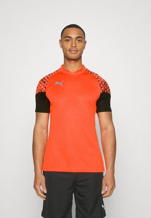 Puma sportshirt in een levendige oranje kleur met zwarte korte mouwen. Heeft een driehoekig patroon op de schouders en een blauw logo op de borst.