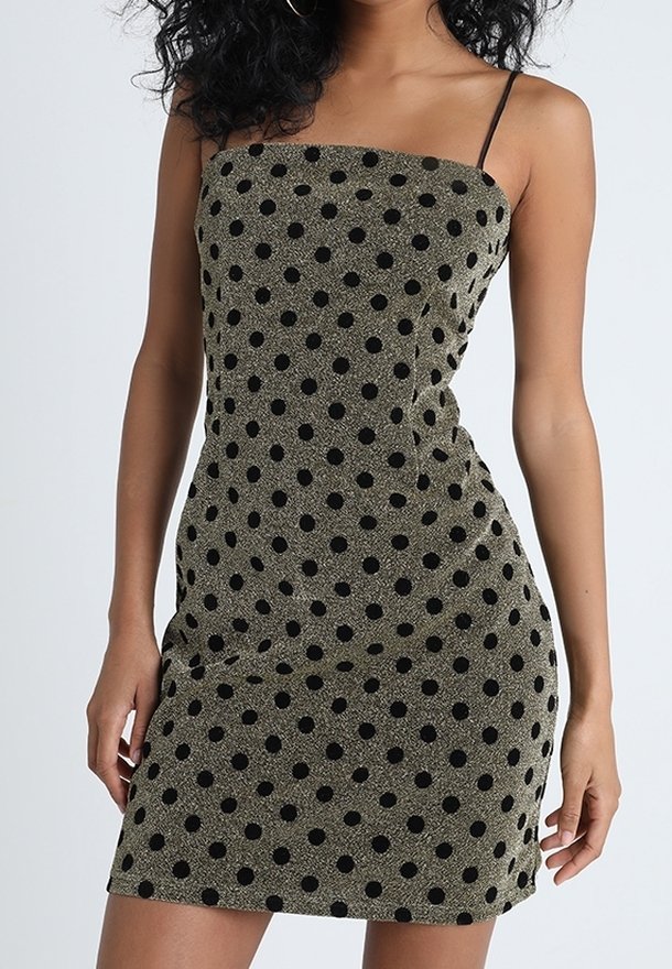 Ärmlös, figurnära miniklänning i olivgrön med svarta polka prickar. Har tunna axelband och ett slätt, strukturerat tyg.