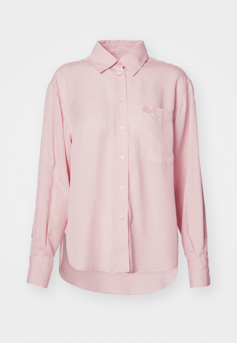 Chemise à manches longues rose pâle, avec un col, une poche poitrine unique et un logo brodé. Fabriquée en tissu coton lisse.