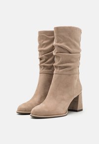 Beiga mockaimuddar med en slouchad design, rund tå och en grov klack. Slät yta med minimala sömnadsdetaljer.