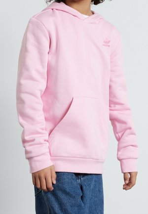 Różowa bluza z kapturem wykonana z miękkiego materiału, z przednią kieszenią i haftowanym logo na piersi. Idealnie komponuje się z niebieskimi dżinsami.