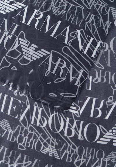 Σκούφος από σκοτεινό ύφασμα με επικαλυπτόμενο λευκό κείμενο "ARMANI" και επαναλαμβανόμενα μοτίβα με το λογότυπο αετού, με κρόσσια στα άκρα.