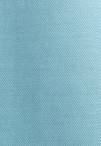 Gros plan sur un tissu bleu clair avec de fines rayures blanches en diagonale, formant un motif en chevrons.