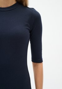 Morska haljina rebraštog dizajna s uskim krojem, kratkim rukavima i visokim izrezom, s glatkom teksturom i suptilnim detaljima šavova.