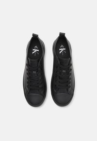 Paire de baskets basses noires avec lacets noirs et semelles intérieures de marque, affichées côte à côte sur un fond blanc uni.