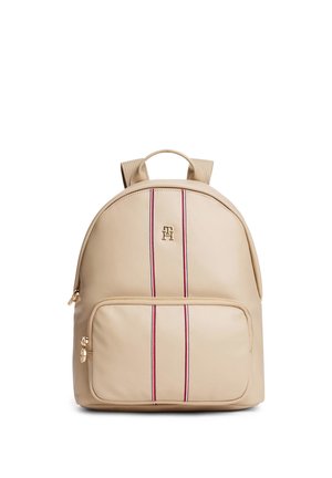 Beige rugzak met voorvak met rits, dubbele verticale rode en witte strepen, goudkleurig logo en verstelbare schouderbanden.