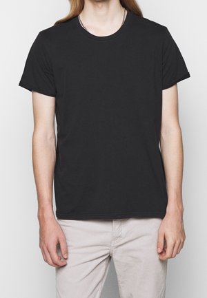 Black cotton t-shirt with short sleeves and a crew neckline. Features a straight cut and minimal detailing, worn with light-colored pants.