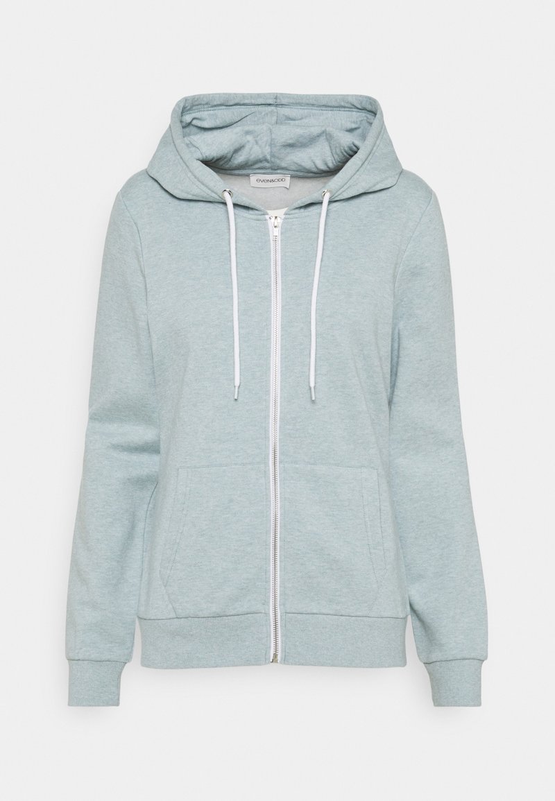 Sweat à capuche bleu clair zippé avec poches avant, cordons blancs, poignets côtelés et capuche, présenté sur un fond uni.