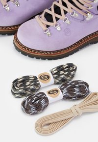 Purple suede hiking boots with beige laces, accented by metallic eyelets; paired with three bundles of shoe laces in various colors and patterns.