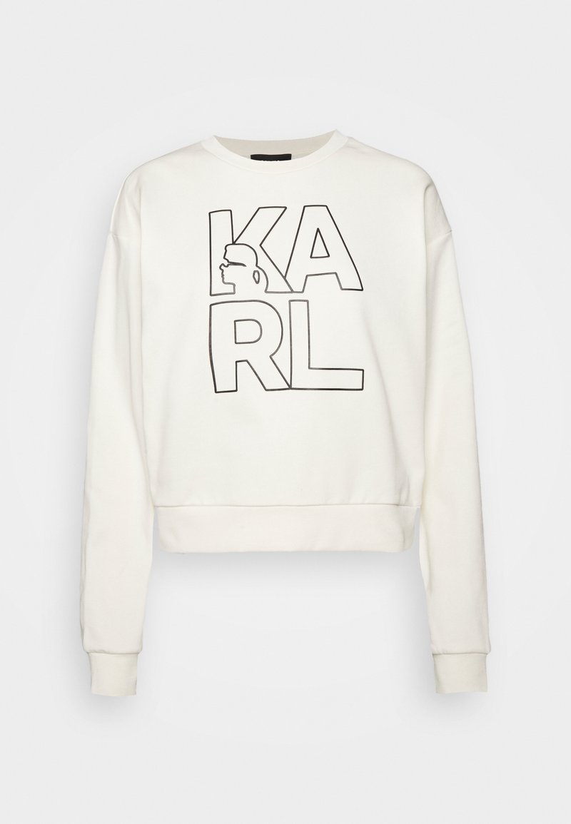 Sweat-shirt blanc à manches longues avec des lettres noires en contour formant le mot « KARL » et une silhouette de profil latéral incorporée dans le « K ».