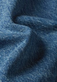 Denim w jednolitym średnim niebieskim kolorze, prezentujący miękką fakturę z subtelnymi odcieniami oraz gęsto tkanym wzorem.