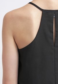 Top negro sin mangas con un diseño posterior elegante que presenta una abertura en forma de llave y tirantes finos, confeccionado en una tela suave y ligera.