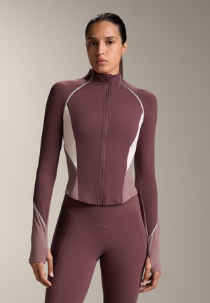 Giacca sportiva zip-up color bordeaux con maniche lunghe, accenti bianchi e design crop. Texture liscia con dettagli riflettenti lungo le cuciture.