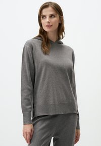Grijze hoodie met lange mouwen en een ontspannen pasvorm. Heeft een gestructureerde, zachte stof met zijsplitten aan de zoom.