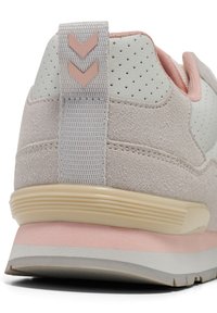 Sneaker grigio chiaro con finitura in suede testurizzato, dettagli rosa e suola in gomma a contrasto. Presenta un'etichetta con dettaglio a chevron sul tallone.