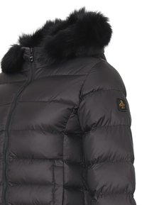 Giacca a vento nera con cappuccio foderato in pelliccia, chiusura frontale con zip e design trapuntato con una patch del logo sulla manica. Materiale morbido e lucido.