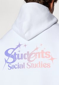White hoodie with a large graphic in gradient colors of purple and pink, featuring "Students Social Studies" and decorative star accents.