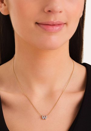 Gouden ketting met een met diamanten bezette "W" hanger. De schakels zijn dun en delicaat, wat het elegante ontwerp aanvult.