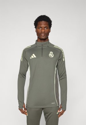 Langermet treningstopp i olivengrønn med en kvart glidelås, kontrasterende lysegrønne sidepaneler, og Real Madrid-logo på brystet.
