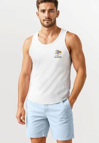 White sleeveless tank top with palm tree and sun graphic; light blue shorts with side pockets; smooth fabric and relaxed fit.
