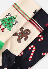 Calcetines con diseño que presentan un árbol de Navidad verde, un hombre de jengibre y bastones de caramelo rojos y blancos sobre fondos crema y azul marino.