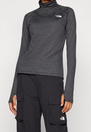 Person wearing a fitted gray waffle-texture turtleneck and black cargo pants, both with The North Face logos.