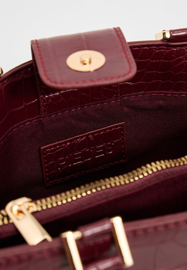 Sac à main en simili cuir bourgogne avec texture crocodile embossée, quincaillerie dorée et intérieur zippé, dotée d'une étiquette de marque et d'une doublure lisse.