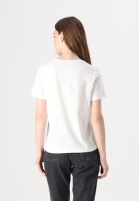 T-shirt in cotone bianco con maniche corte e scollo rotondo, posizionato su uno sfondo neutro, con una vestibilità morbida e una texture liscia.