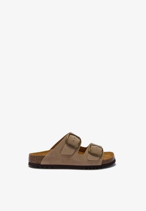 Beige suède sandaal met open tenen, twee verstelbare bronzen gespen en een kurken zool met een zwarte rubberen onderkant.