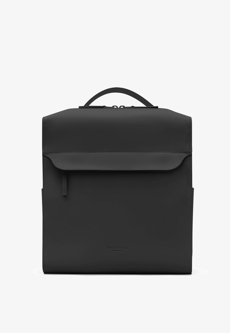 Sac à dos structuré noir avec poignée supérieure, poche avant à rabat avec fermeture éclair, et logo de marque subtilement embossé en bas au centre.