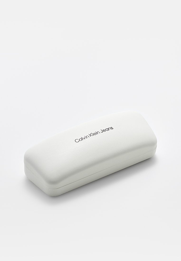 Biały prostokątny futerał na okulary z zaokrąglonymi krawędziami, z napisem "Calvin Klein Jeans" wyśrodkowanym na górnej powierzchni.