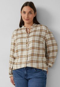 Langarm geruite blouse in crème, bruin en goud met knoopsluiting en strik halslijn. Zachte stof met een relaxte pasvorm en elastische manchetten.