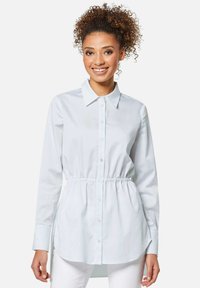 Hellblaues Button-Up-Hemd aus Baumwolle mit tailliertem Schnitt, langen Ärmeln und einem klassischen Kragen mit einer glatten Textur.