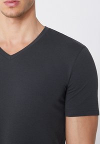 Camiseta gris de cuello en V hecha de una suave tela de algodón, con mangas cortas y un diseño limpio y simple sin patrones ni acentos adicionales.