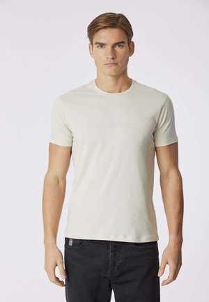 T-shirt beige chiaro realizzata in tessuto morbido, con maniche corte e scollo rotondo, caratterizzata da un logo tonale "USPA Sport" sul davanti.