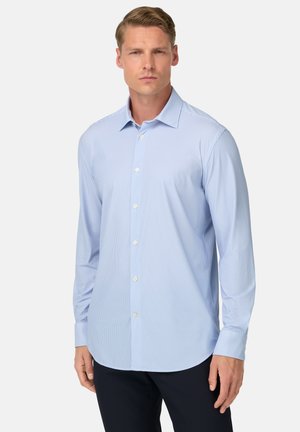 Camisa de vestido de manga larga, de color azul claro, con rayas blancas, con botones en la parte delantera y cuello extendido. La tela parece suave y con textura.