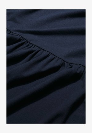 Ciemnoniemiecki materiał z falbaną zgromadzoną wzdłuż szwu, prezentujący miękką teksturę i gładkie wykończenie.